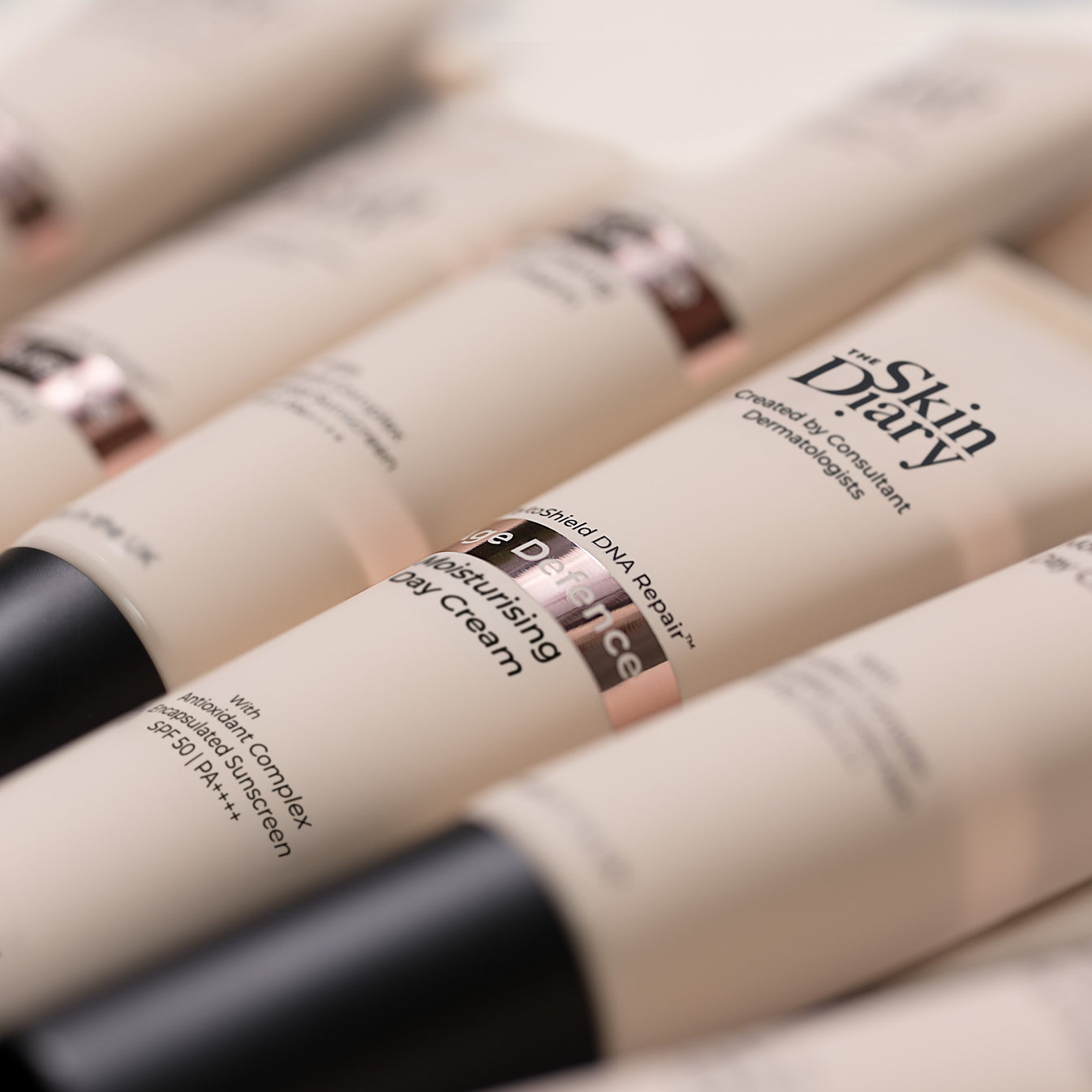 A close-up diagonal arrangement of The Skin Diary Age Defence tubes on a clean white background.