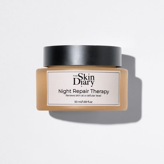 A jar of The Skin Diary Night Repair Therapy cream with a black lid and a amber glass container, shown on a white background with a soft shadow.
